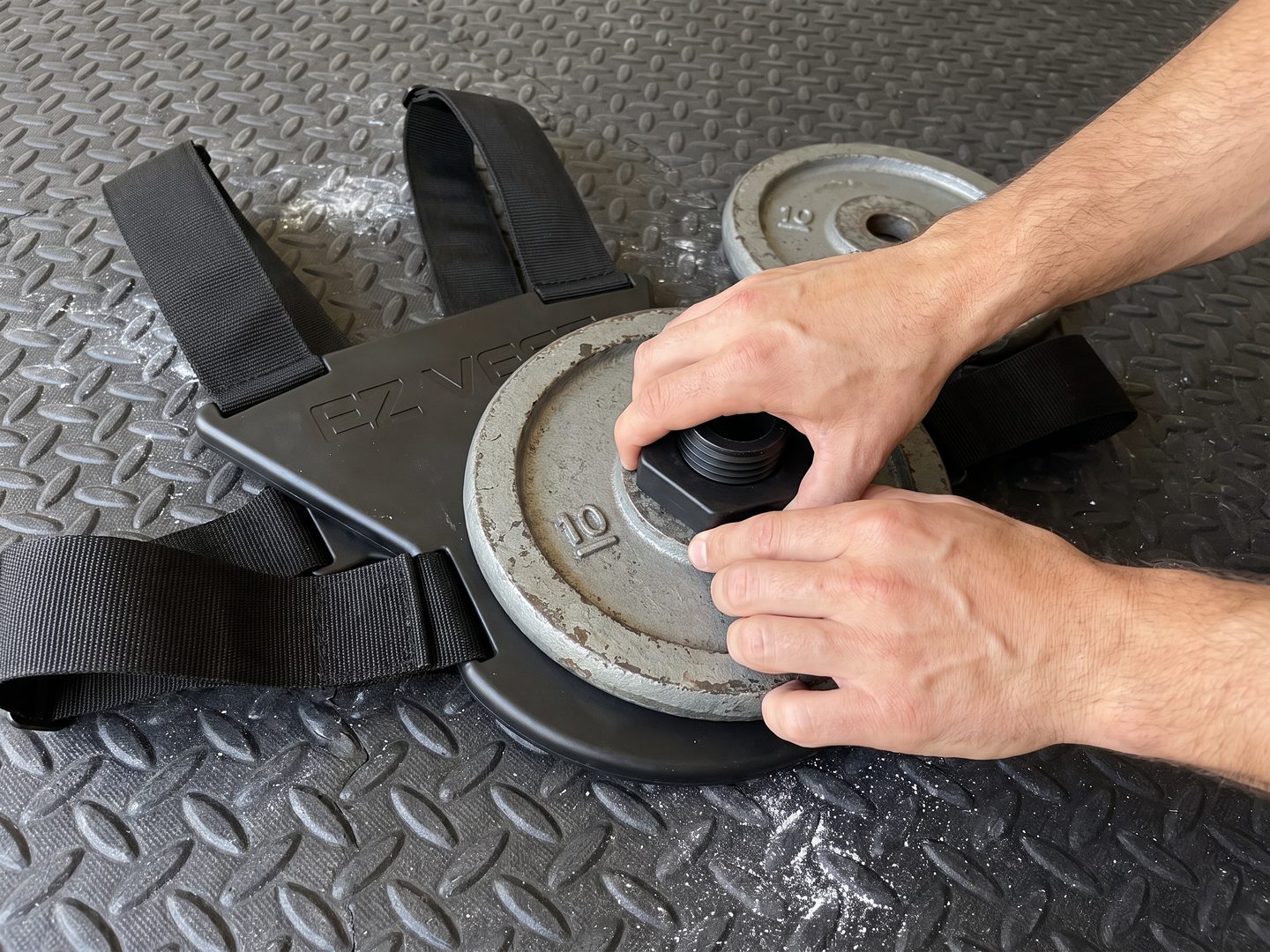 Two hands spinning the black collar onto the short post of the EZ-VEST Lite to lock an old 10 pound plate in place