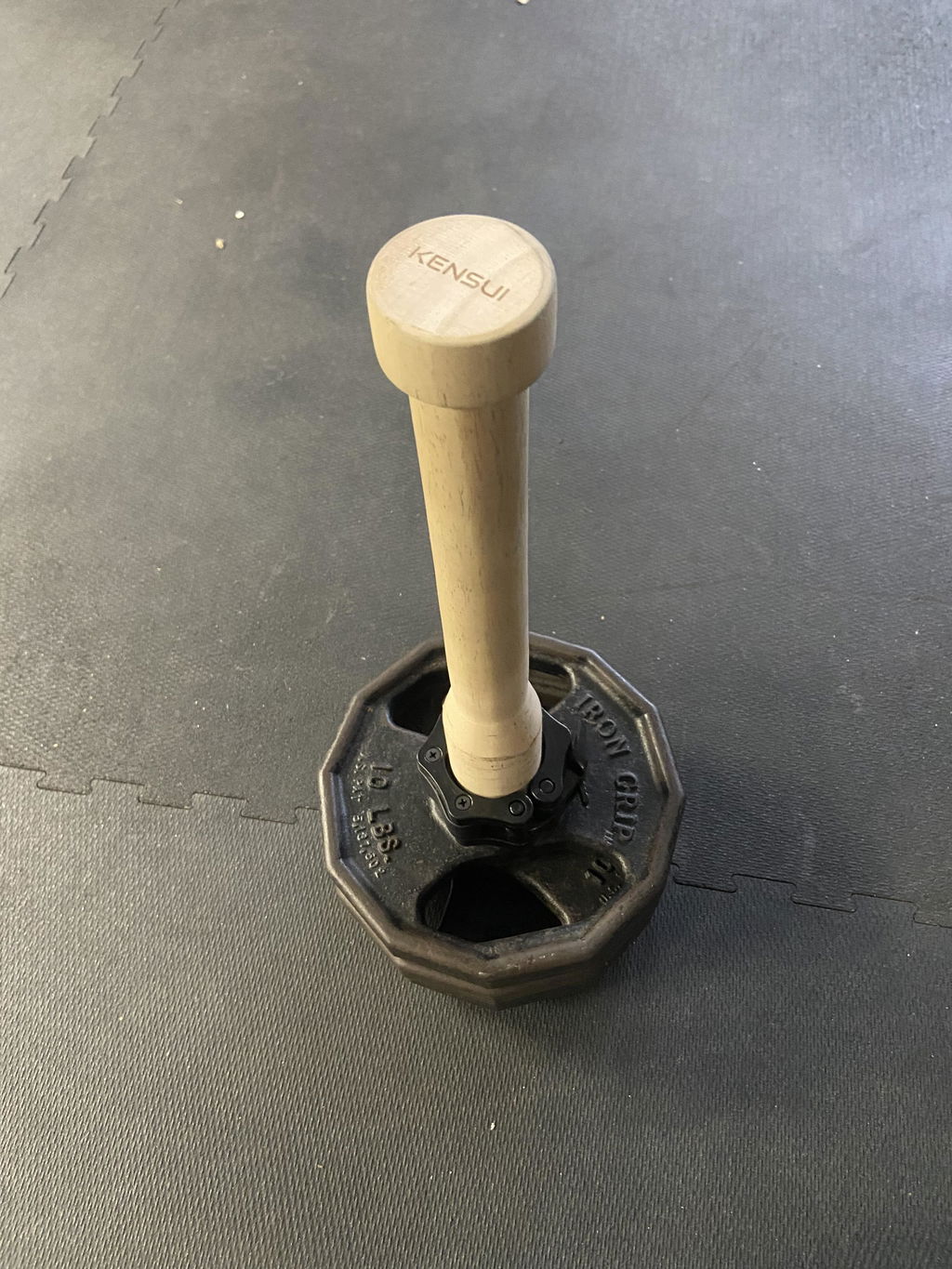 Loaded training club standing upright on a gym tile