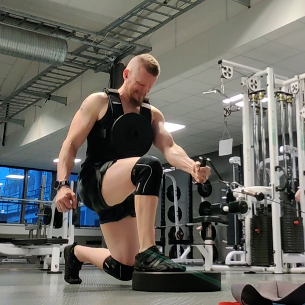 Lifter wearing a loaded weight vest during a step-up in a gym