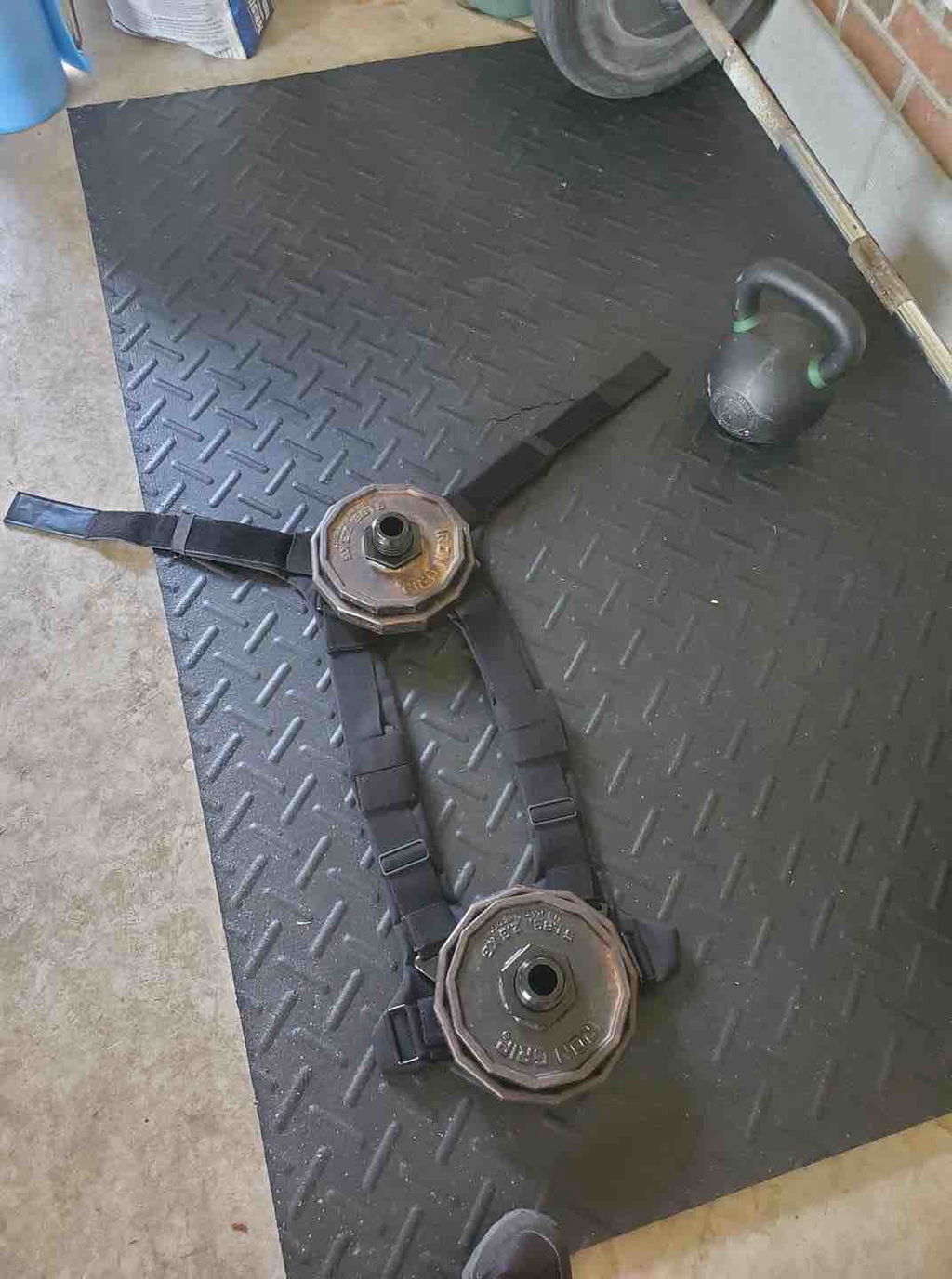 Vest straps and loading posts laid out on a rubber gym floor