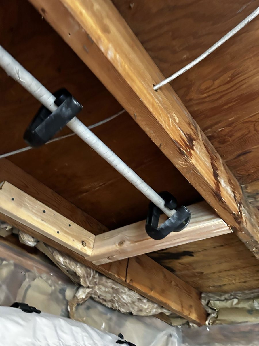 A pair of Swissies handles hooked over a ceiling-mounted pull-up bar in a basement