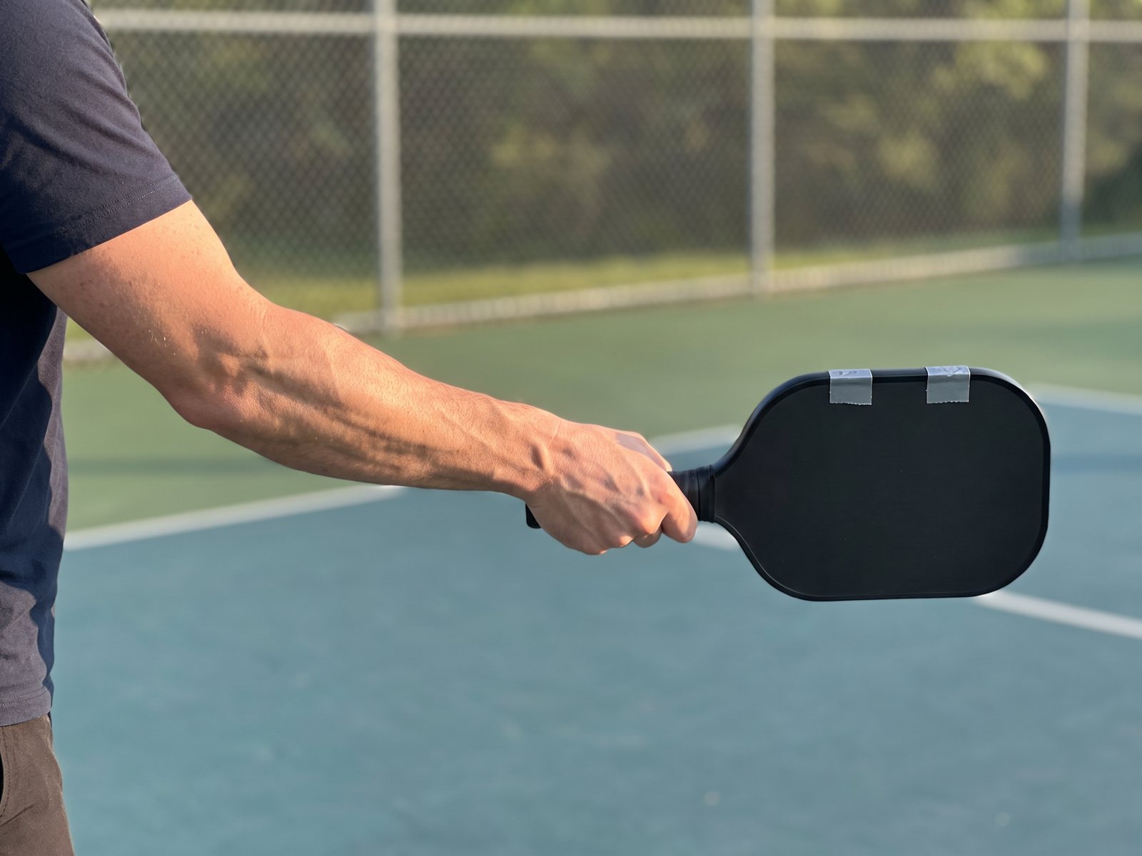 A close view of the author's forearm holding a paddle straight out like a lever, two strips of lead tape along its top edge